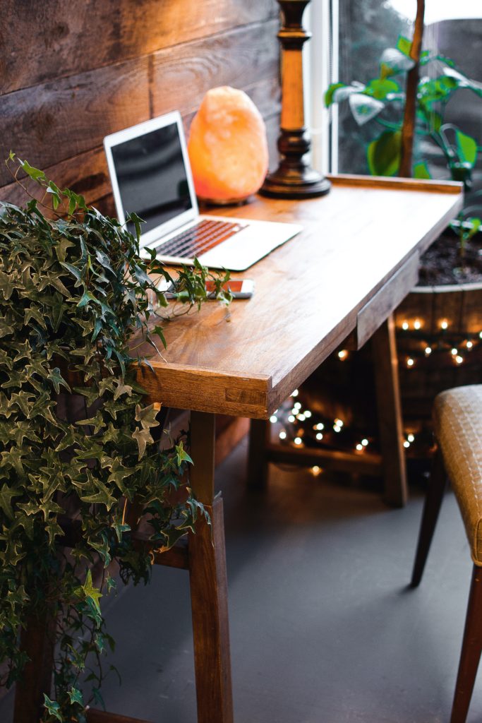 Workspace with wood writing desk with laptop and green plant