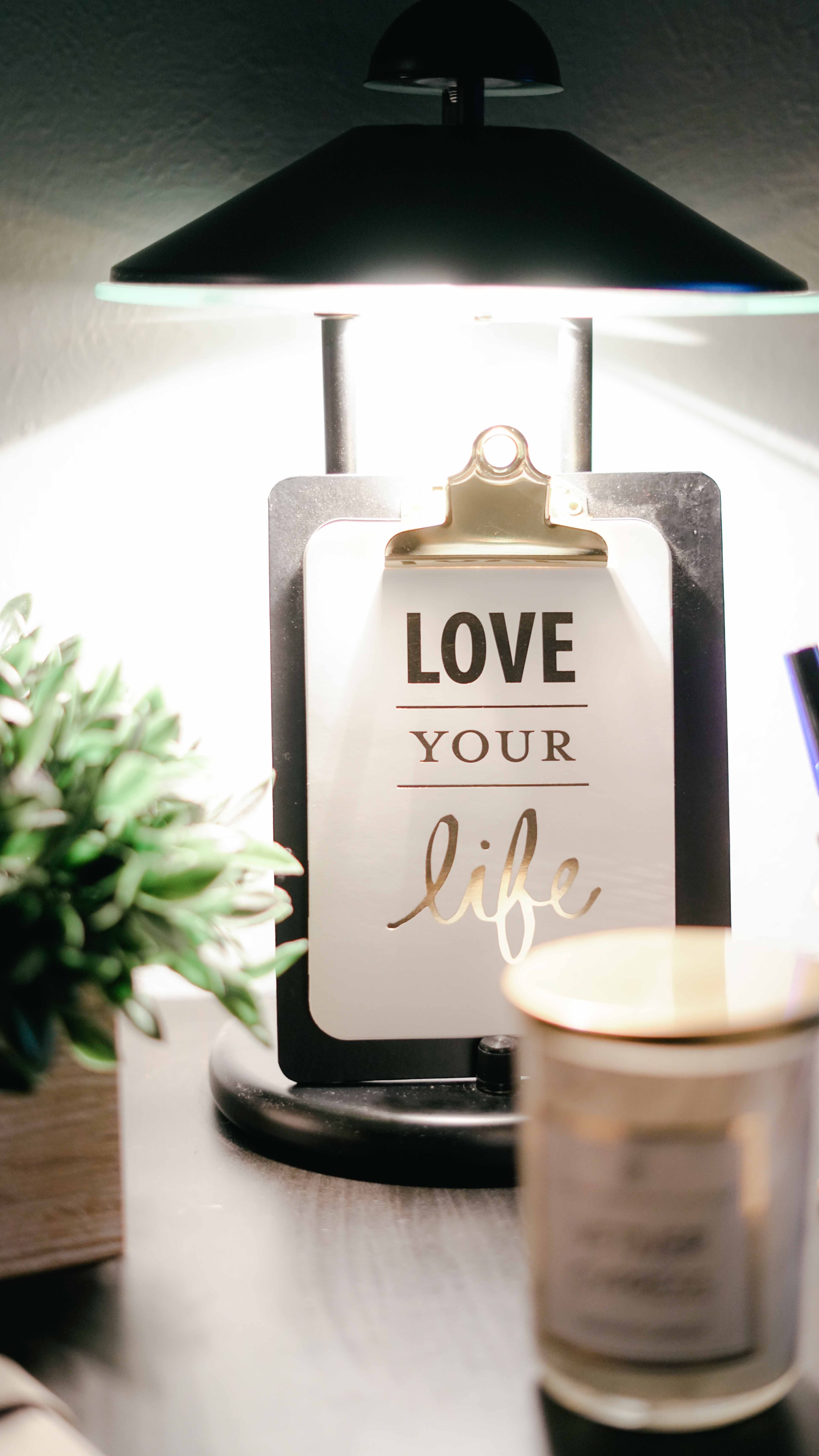 Lamp on desk with clipboard and a written encouragement to Love Your Life