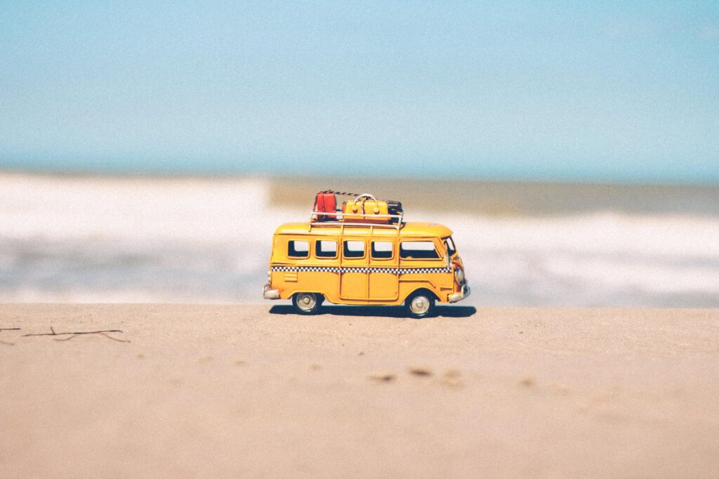yellow van die cast on sand symbolizes a road trip to the beach.