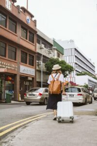 view of a woman on city street pulling a suitcase to an in-person meetup with online friends